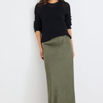 Woman wearing a black sweater and green skirt against a white background