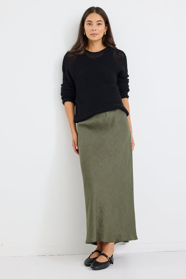 Woman wearing a black sweater and green skirt against a white background