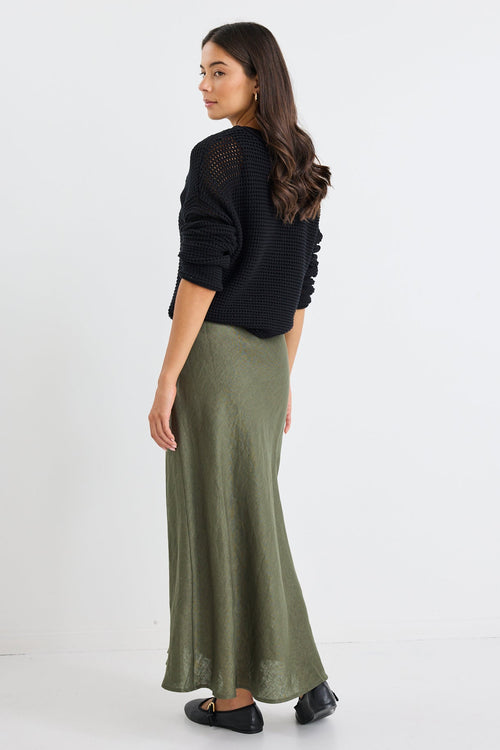 Woman wearing a black top and green skirt on a white background