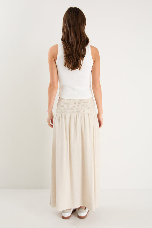 model wears a natural linen maxi skirt with a white tank top