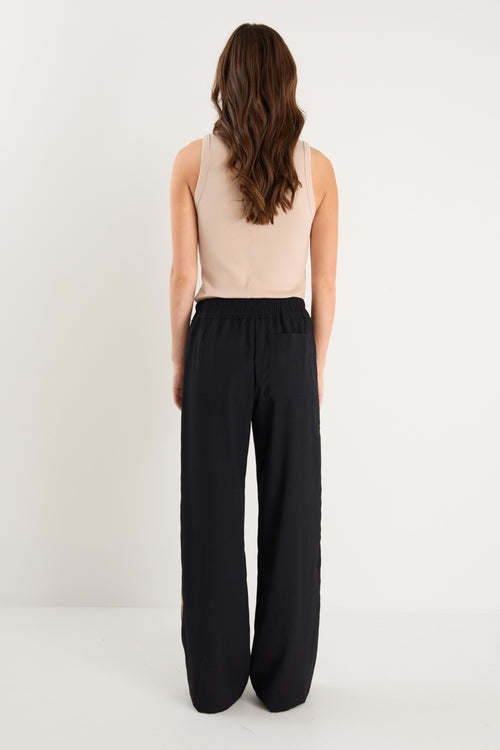 Woman wearing a beige top and black pants on a white background