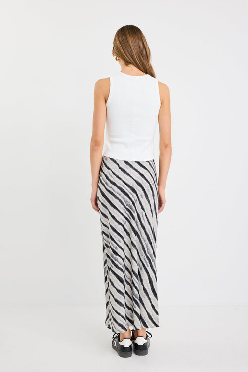 Woman wearing a white sleeveless top and zebra-striped skirt on a white background