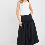 Woman wearing a white sleeveless top and black skirt on a white background