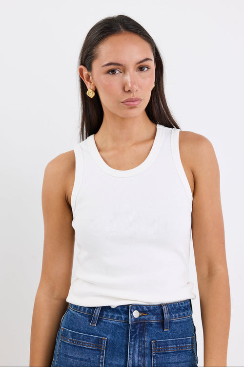Woman wearing white sleeveless top with blue jeans