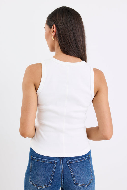 Woman wearing white sleeveless top with blue jeans
