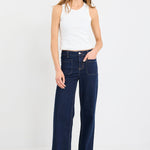 Woman wearing a white top and dark blue jeans on a white background