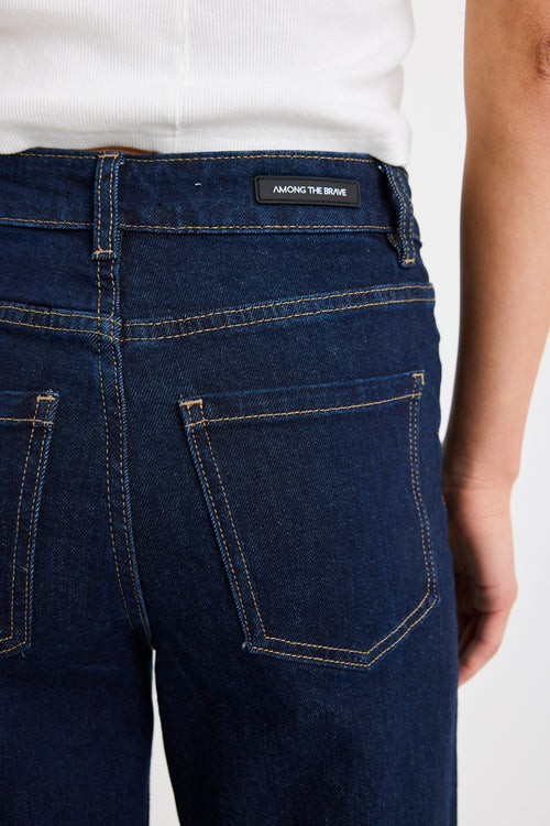 Close-up of dark blue jeans with a brand label on a white background
col_pattern
