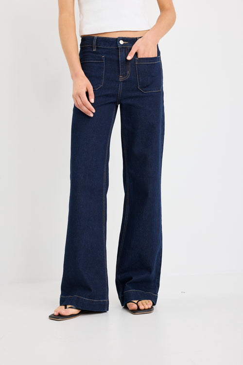 Person wearing dark blue flared jeans on a white background