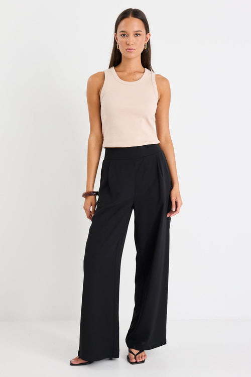 Woman wearing a black pant and beige tank