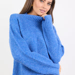 Woman wearing a blue sweater and jeans on a white background