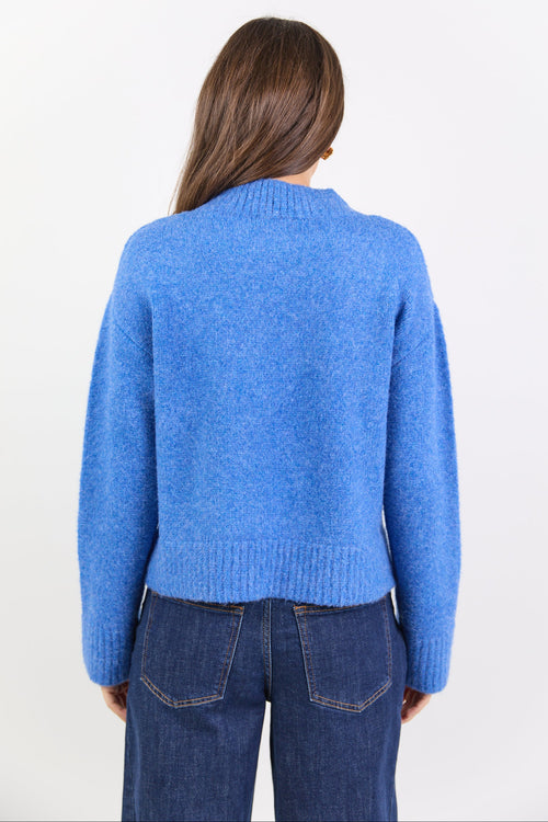 Person wearing a blue sweater and jeans on a white background
