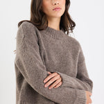 Woman wearing a gray sweater against a white background
