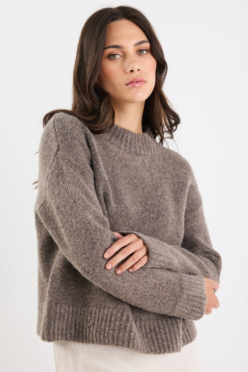 Woman wearing a gray sweater against a white background