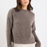 Woman wearing a brown sweater against a white background