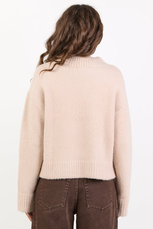 Person wearing a beige sweater and brown pants on a white background