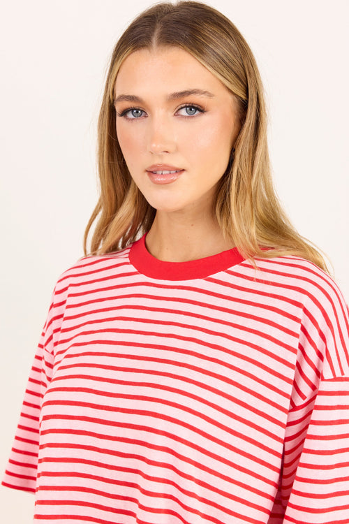A woman wearing a red and white horizontally striped short-sleeve t-shirt with a solid red crew neck, photographed against a clean off-white background.
