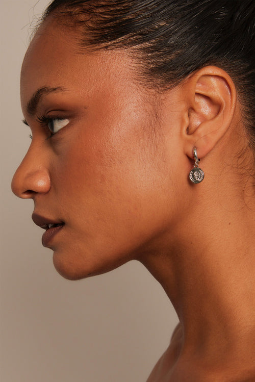 model wearing coin huggie earrings
