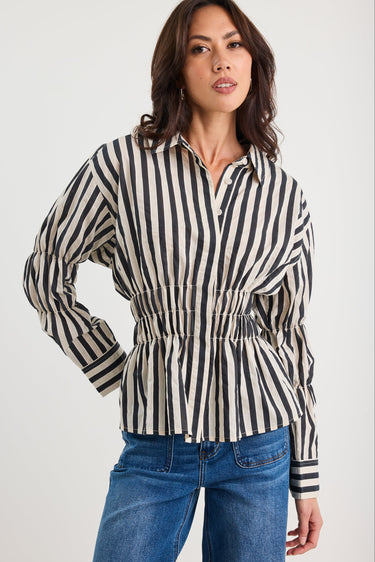 Woman wearing a black and white striped shirt with blue jeans on a white background