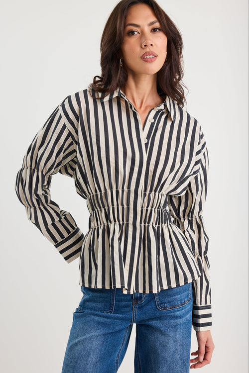 Woman wearing a black and white striped shirt with blue jeans on a white background