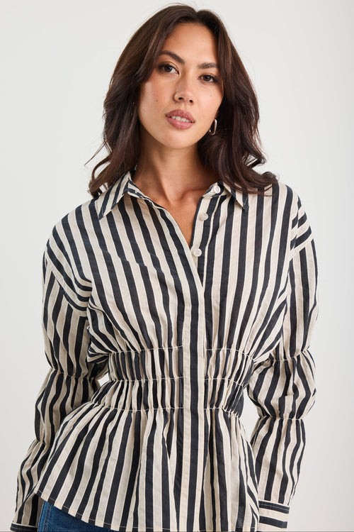 Woman wearing a black and white striped shirt against a plain background