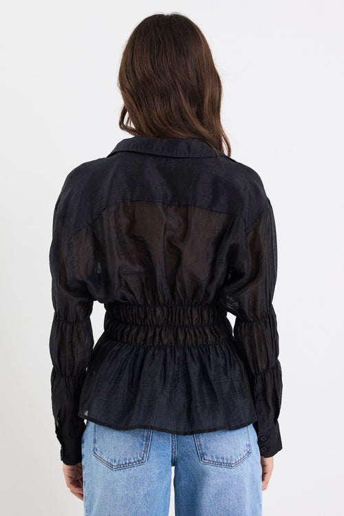 Person wearing a black jacket and blue jeans on a white background