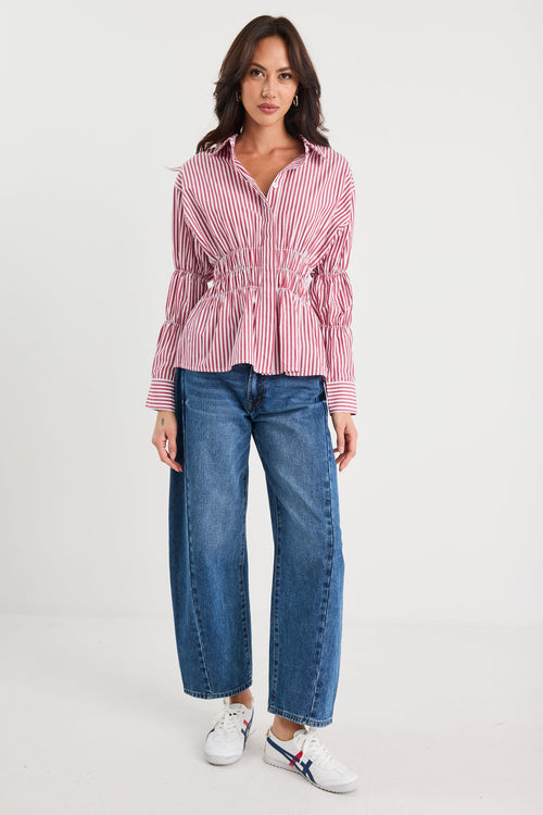 Woman wearing a red and white striped shirt with blue jeans on a white background