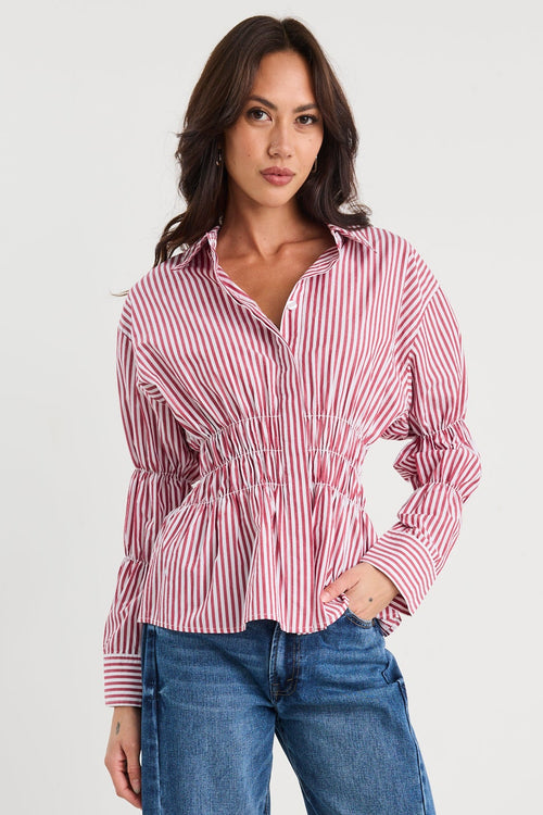 Woman wearing a red and white striped shirt and blue jeans on a white background