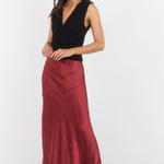 Woman wearing a black top and burgundy skirt on a white background