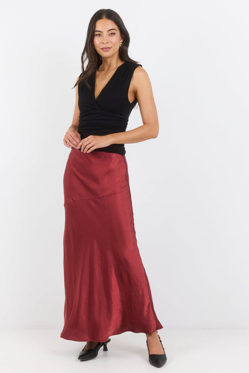 Woman wearing a black top and burgundy skirt on a white background