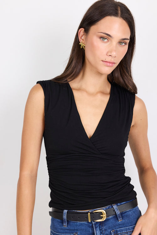 Woman wearing a black sleeveless top and blue jeans on a white background