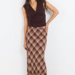 Woman wearing a brown top and patterned skirt on a white background