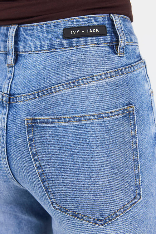 Close-up of blue jeans with 'Ivy + Jack' label on a white background