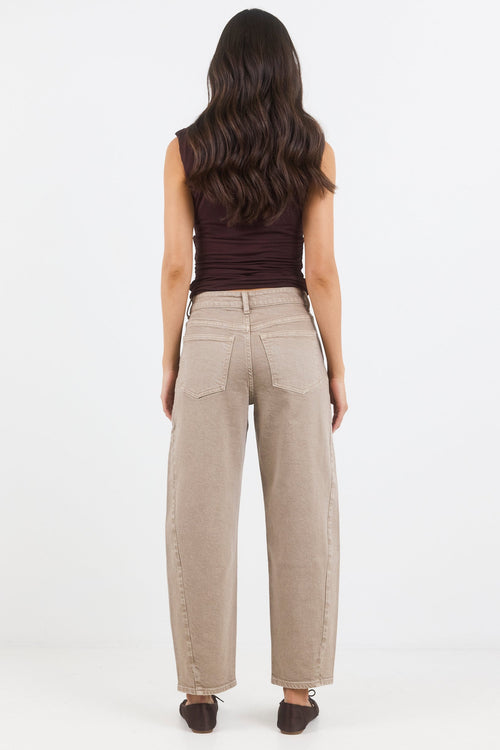 Woman wearing beige pants and a brown top on a white background