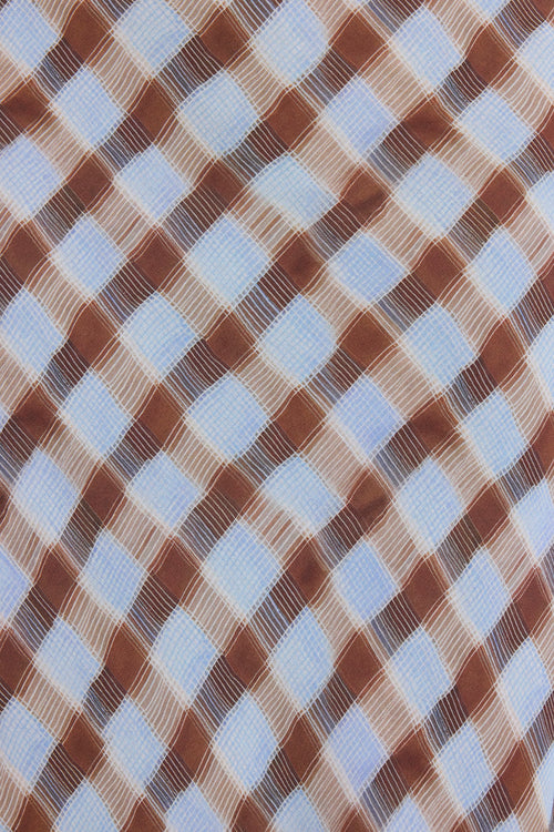 A close-up of a woven fabric with a diagonal diamond check pattern in brown, beige, and light blue.
