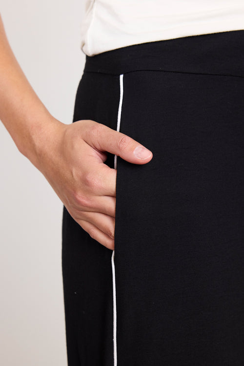 Person with hand in pocket, wearing black pants with a white background