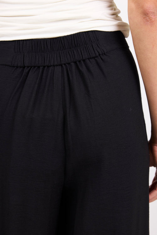 Black pants worn by a person on a white background