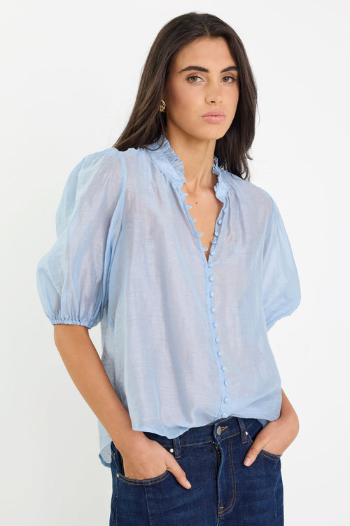 Woman wearing a light blue blouse with puffed sleeves and dark jeans on a white background
col_pattern