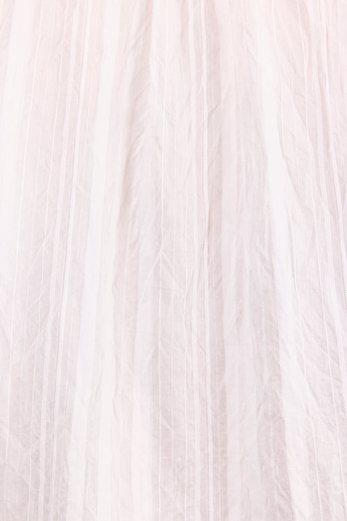 A close-up of a light blush pink pleated fabric, showing the delicate texture and vertical folds.
