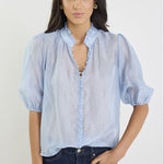 Woman wearing a light blue blouse with puffed sleeves against a white background