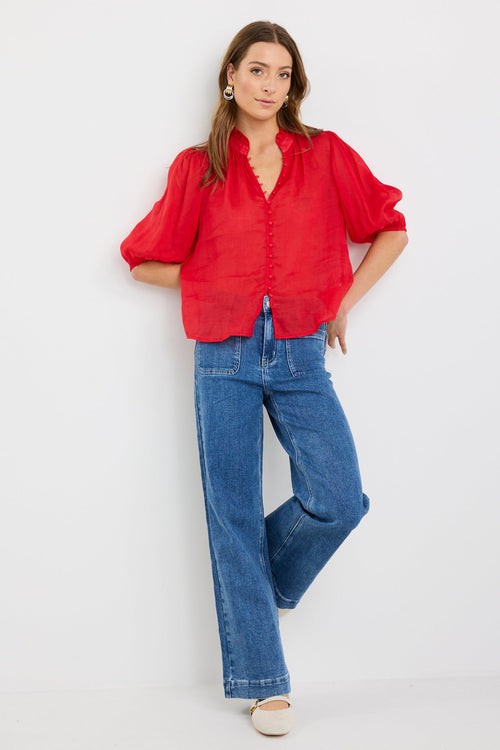 Woman wearing a red blouse and blue jeans on a white background