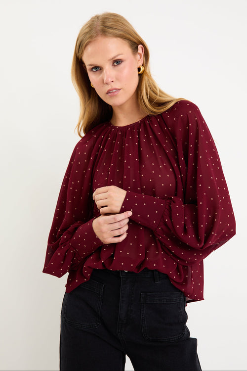 Model wearing a burgundy long sleeve polka dot blouse with a floaty fit, crew neckline and balloon sleeves.