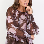 Woman wearing a brown floral blouse against a white background