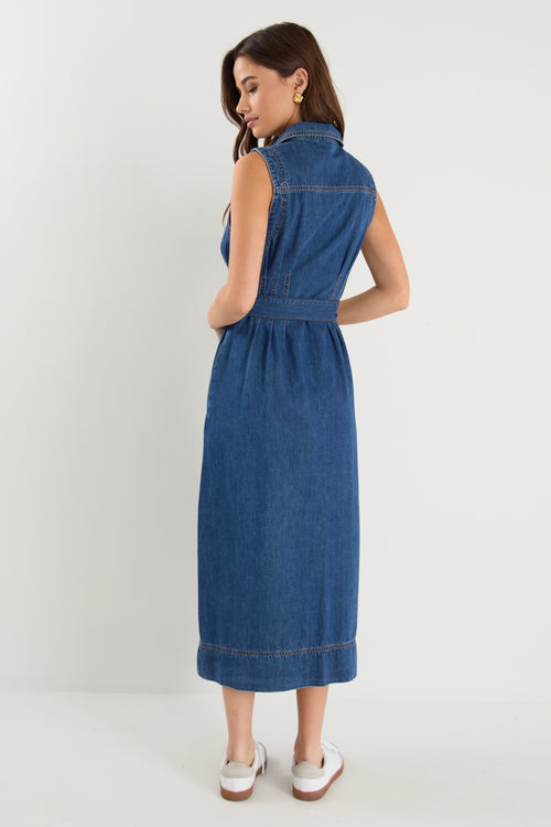 Model wears a sleeveless denim midi dress with white sneakers