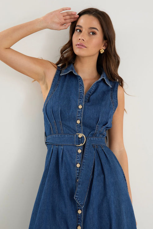 Model wears a sleeveless denim midi dress with white sneakers