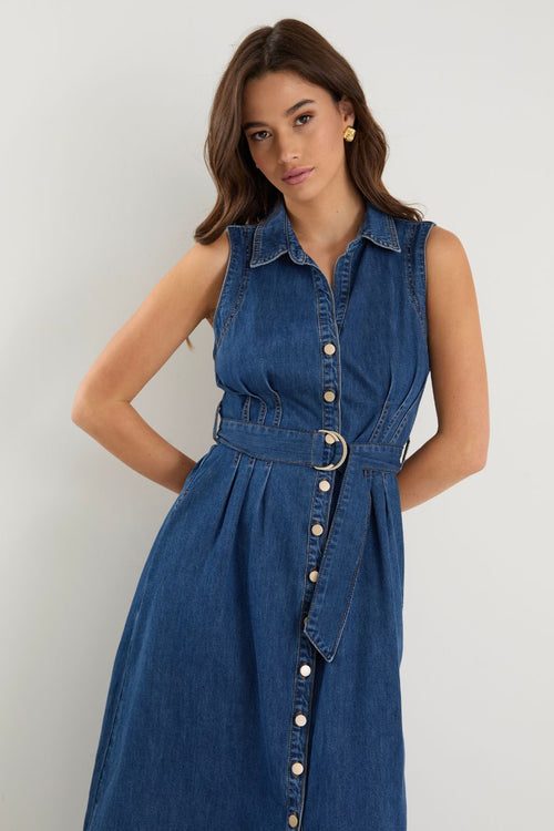 Model wears a sleeveless denim midi dress with white sneakers