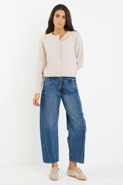 Woman wearing a beige jacket and blue jeans on a white background