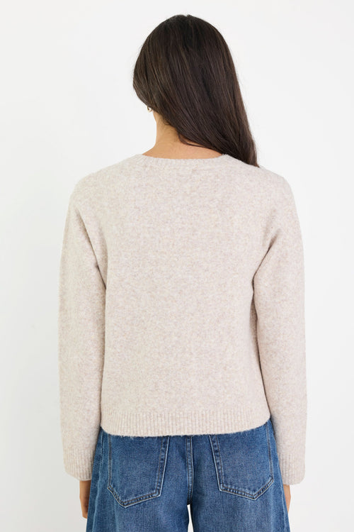 Person wearing a beige sweater and blue jeans on a white background