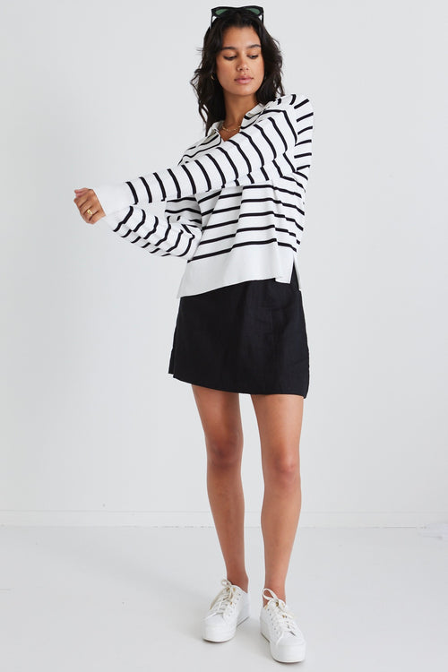 model wears a striped black and white jumper and black skirt with white sneakers