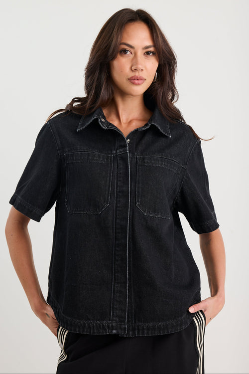 Woman wearing a black denim shirt against a white background