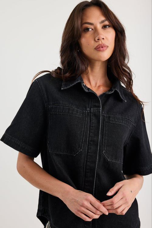 Woman wearing a black denim shirt against a white background